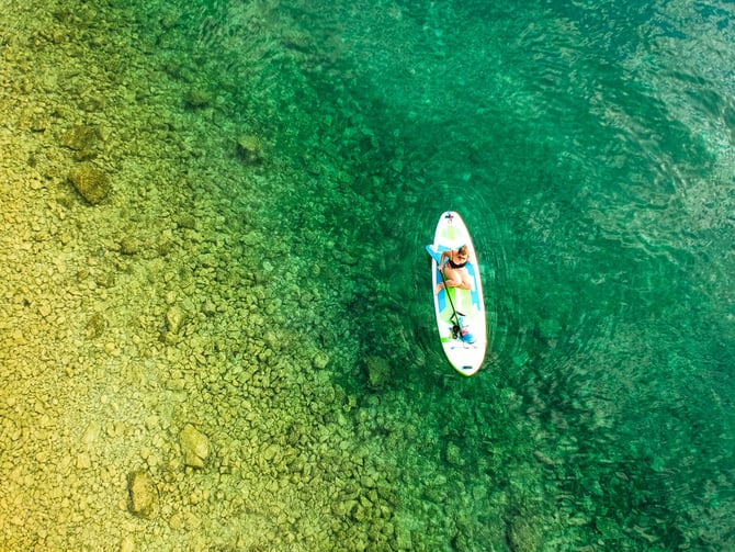 Aerial view of a paddleboarder on clear turquoise water
